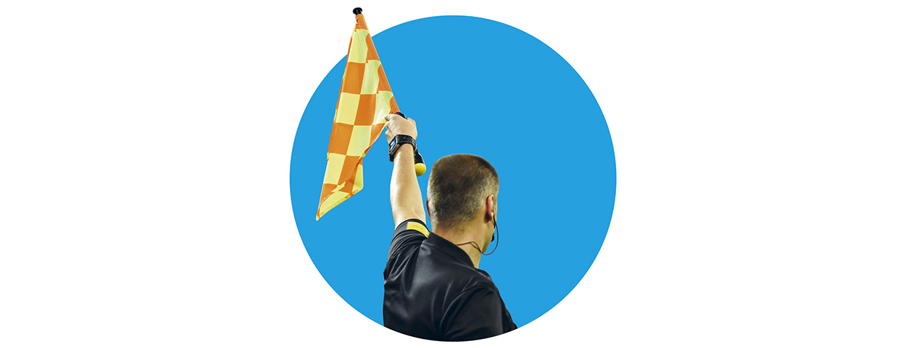 Jalkapallotuomari nostaa keltaisen lipun paitsion merkiksi