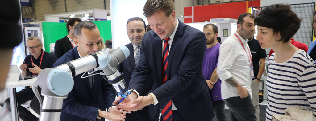Ministeri Ville Skinnari tutustuu teollisuusrobottiin teknologiamessuilla Istanbulissa.