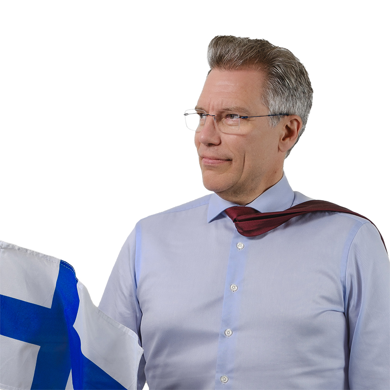 Työ- ja elinkeinoministeriön osastopäällikkö Riku Huttunen katsoo sivuttain solmio tuulessa heiluen kohti kameraa.