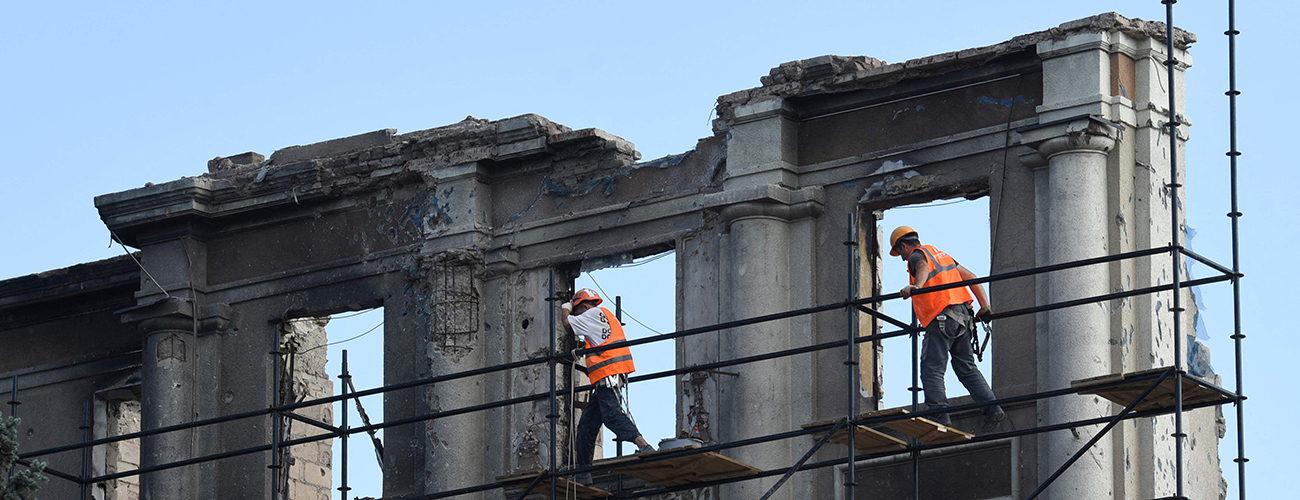 Rakennustyömiehet kunnostavat tuhoutunutta rakennusta.