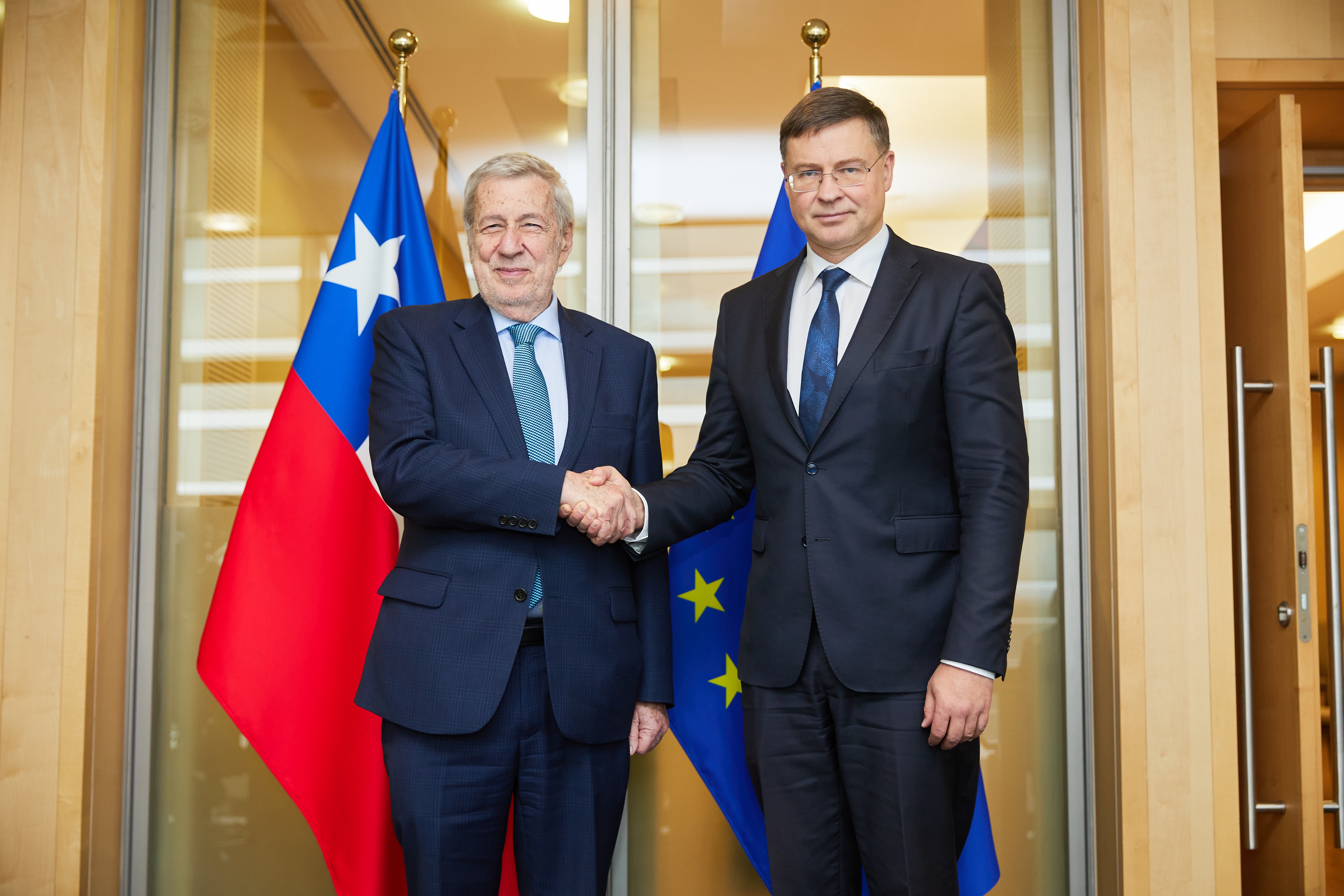 Chilen ulkoministeri Alberto van Klaveren ja komissaari Valdis Dombrovskis kättelevät lippujen edessä.